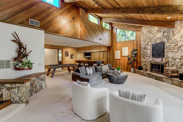 living room with wood ceiling, light carpet, a stone fireplace, and beam ceiling