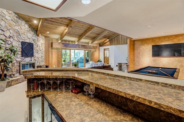 kitchen with open floor plan, wooden ceiling, vaulted ceiling with beams, and a stone fireplace