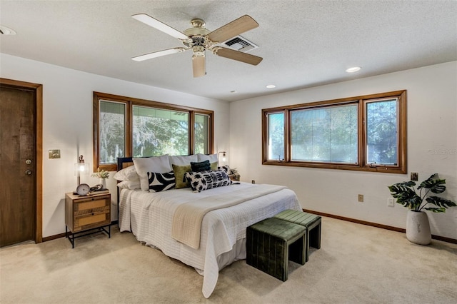 bedroom with visible vents, baseboards, a textured ceiling, and light colored carpet