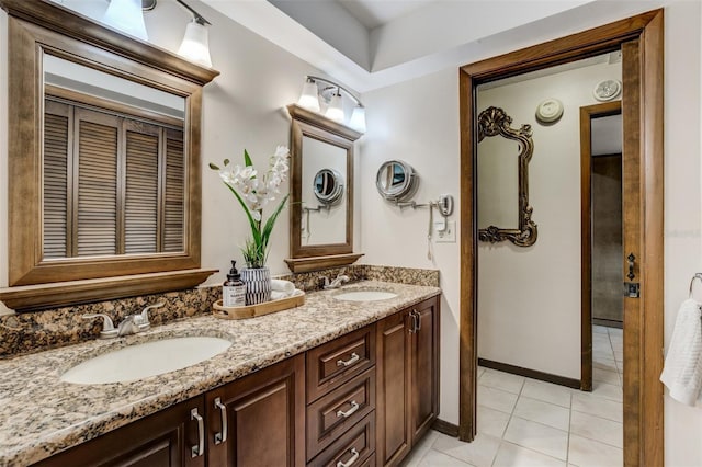 full bath with double vanity, tile patterned flooring, baseboards, and a sink