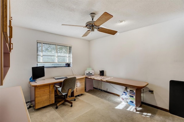 office space featuring a ceiling fan, light carpet, a textured ceiling, and baseboards