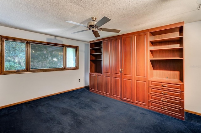 unfurnished bedroom featuring baseboards, dark carpet, ceiling fan, and a textured ceiling