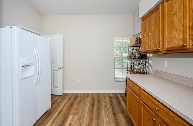18186 Sandy Pointe Dr, Tampa, FL 33647 - kitchen with light countertops, baseboards, brown cabinets, dark wood finished floors, and white refrigerator with ice dispenser