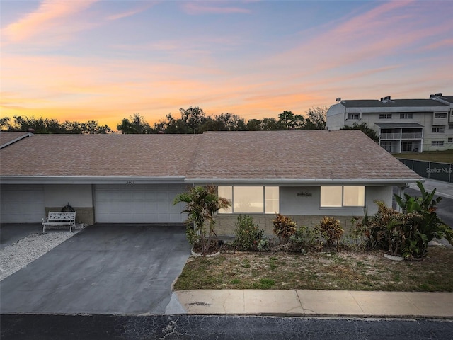 view of front of home with driveway, roof with shingles, a garage, and stucco siding