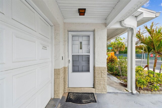 doorway to property featuring a garage and fence