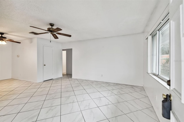 empty room with ceiling fan and a textured ceiling