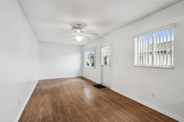 interior space with a textured ceiling, ceiling fan, dark wood-type flooring, and a wealth of natural light