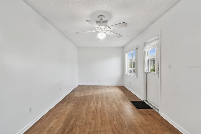 spare room with ceiling fan, a textured ceiling, baseboards, and wood finished floors