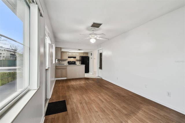 kitchen featuring visible vents, freestanding refrigerator, light wood-type flooring, a sink, and exhaust hood