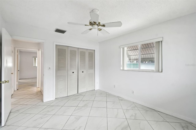 unfurnished bedroom with a ceiling fan, a textured ceiling, visible vents, and a closet