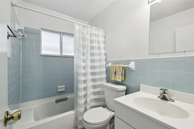 full bath with toilet, shower / bath combo with shower curtain, a textured ceiling, vanity, and tile walls