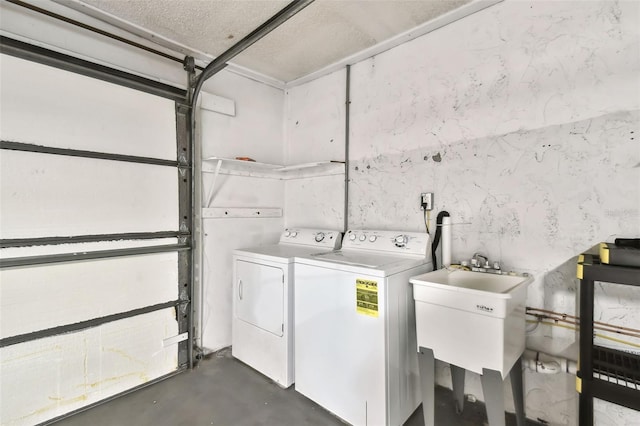 washroom featuring a garage, laundry area, washing machine and dryer, and a sink