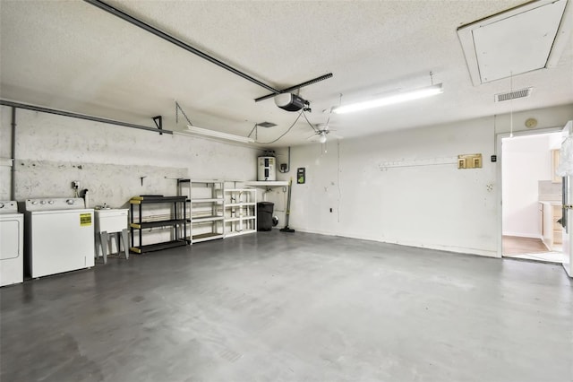 garage with a garage door opener, water heater, visible vents, and separate washer and dryer