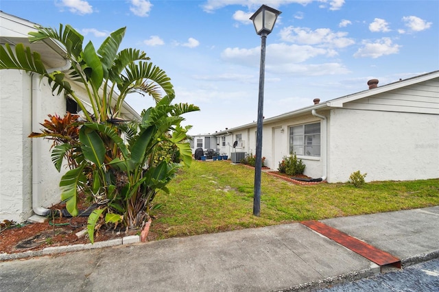 view of property exterior with a yard, central AC unit, and stucco siding