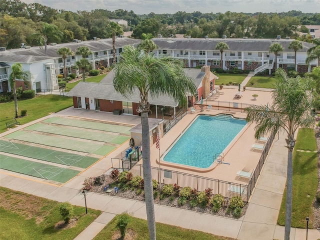 community pool with shuffleboard, a patio, fence, and a residential view