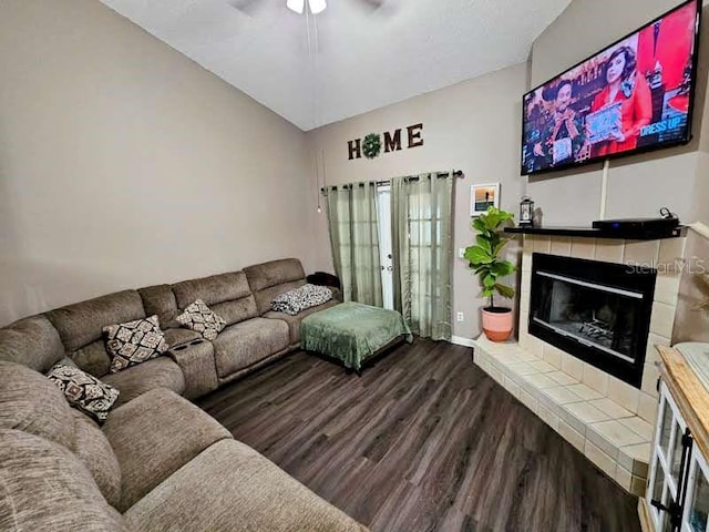 living area featuring vaulted ceiling, ceiling fan, a tile fireplace, and wood finished floors