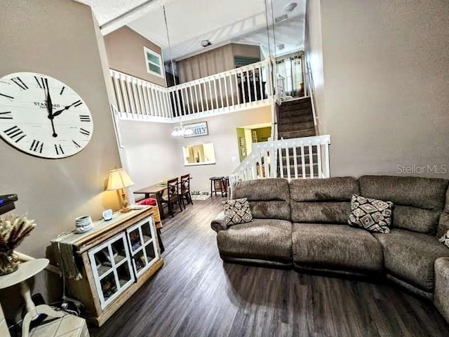 living room with a towering ceiling, stairs, and wood finished floors