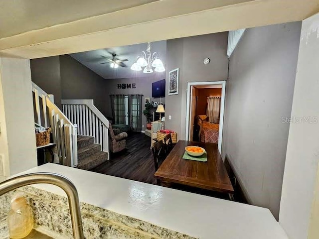 dining space featuring an inviting chandelier, stairs, vaulted ceiling, and wood finished floors