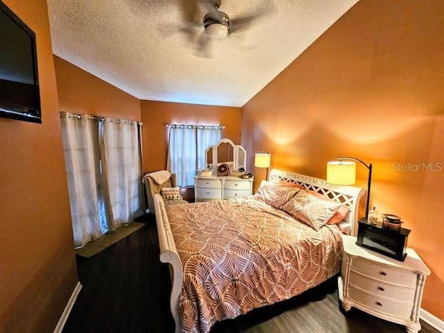 bedroom featuring a ceiling fan, vaulted ceiling, a textured ceiling, wood finished floors, and baseboards