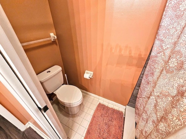 bathroom featuring tile patterned flooring, baseboards, and toilet