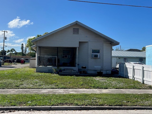 view of front of home with a porch, cooling unit, fence, and a front lawn
