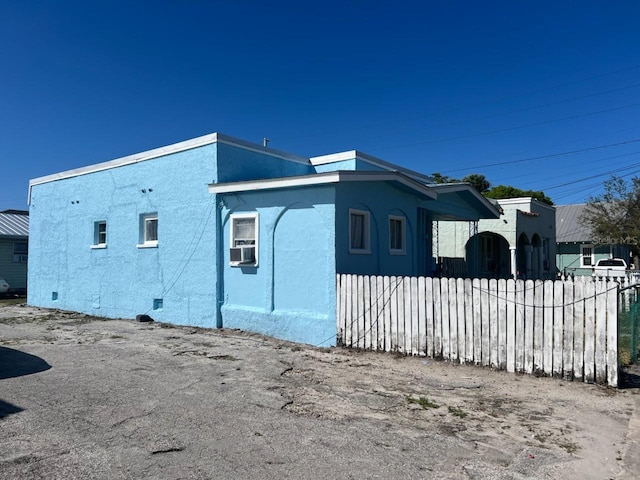 view of side of property with fence, cooling unit, crawl space, and stucco siding