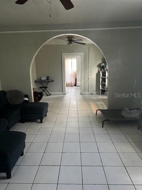hall with arched walkways, a textured ceiling, and tile patterned flooring