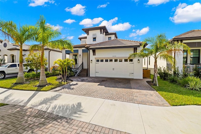 view of front of house featuring a garage, a tiled roof, decorative driveway, and stucco siding