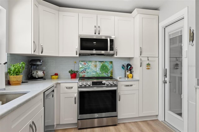 kitchen with appliances with stainless steel finishes, light wood-type flooring, decorative backsplash, and white cabinets