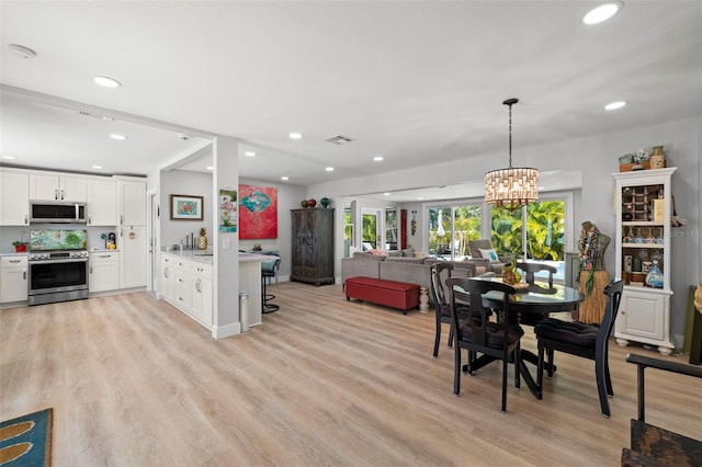 dining area with recessed lighting, visible vents, a notable chandelier, and light wood finished floors