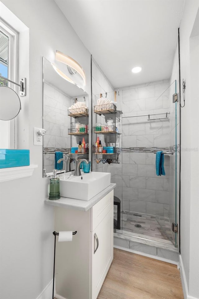 bathroom featuring wood finished floors, a shower stall, and vanity