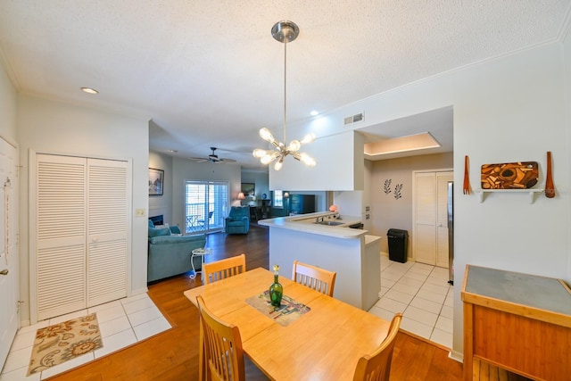 dining area with ornamental molding, visible vents, a textured ceiling, and light wood finished floors