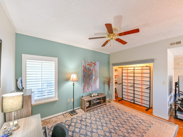 sitting room featuring a textured ceiling, a ceiling fan, visible vents, baseboards, and crown molding