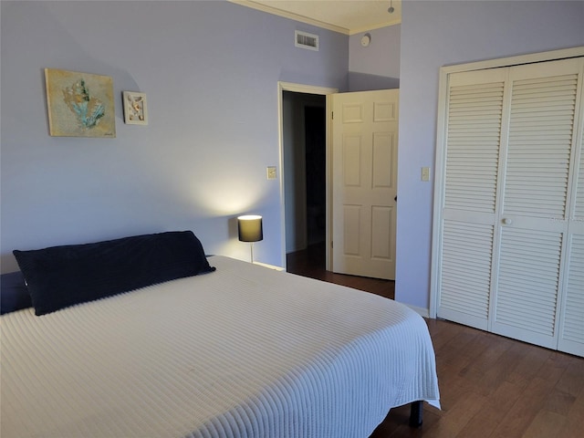 bedroom featuring a closet, dark wood-style flooring, visible vents, and crown molding