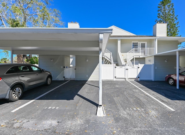 partially covered parking lot featuring a gate and fence