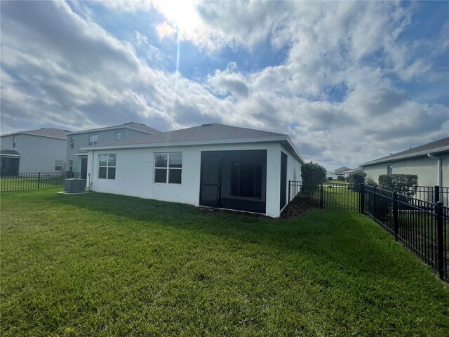 rear view of house featuring a fenced backyard, a lawn, and stucco siding