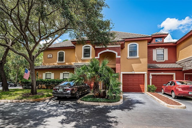 view of front of property featuring an attached garage, driveway, a tiled roof, and stucco siding