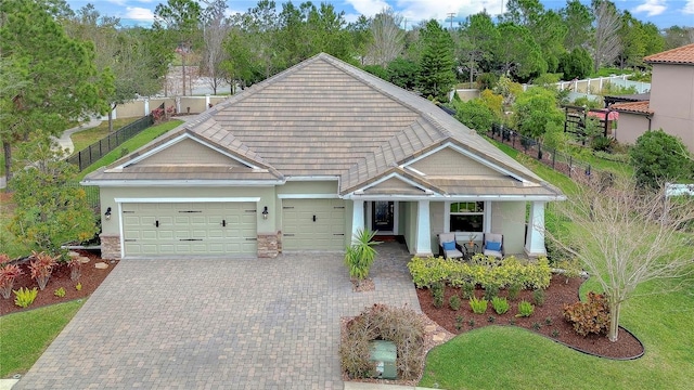 view of front of home with a garage, covered porch, fence, decorative driveway, and stucco siding