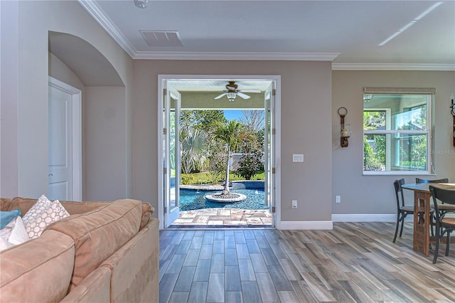 doorway with ornamental molding, visible vents, baseboards, and wood finished floors