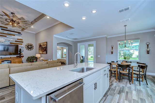 kitchen with stainless steel dishwasher, a sink, visible vents, and light stone countertops