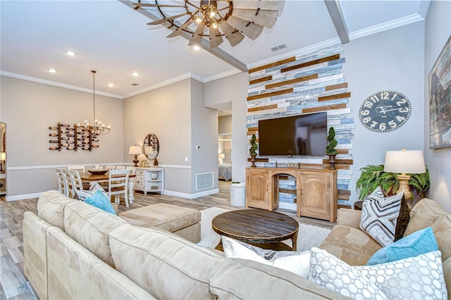 living room with crown molding, visible vents, light wood-style flooring, baseboards, and ceiling fan with notable chandelier