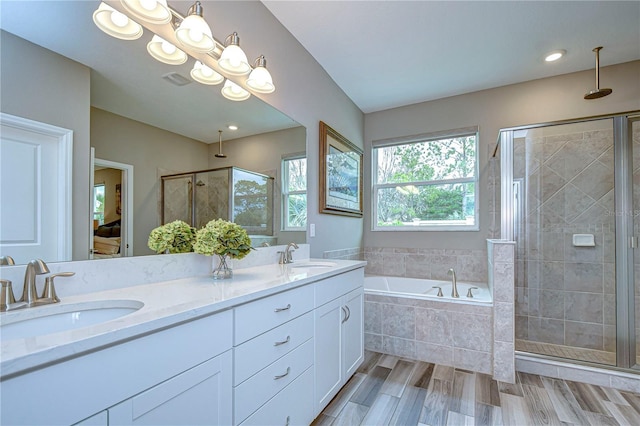 bathroom with a stall shower, a garden tub, a sink, and wood finished floors