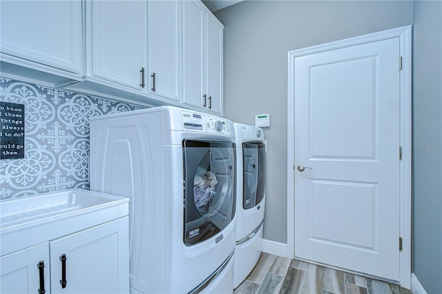 laundry area featuring washer and dryer, cabinet space, light wood-style flooring, and baseboards