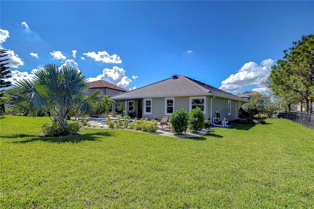 rear view of property with a yard, a patio area, fence, and stucco siding