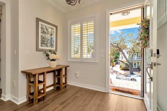 doorway to outside with baseboards, wood finished floors, and crown molding