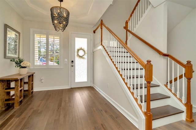 foyer with a tray ceiling, baseboards, crown molding, and hardwood / wood-style floors