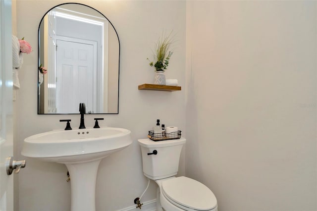 half bath with baseboards and toilet