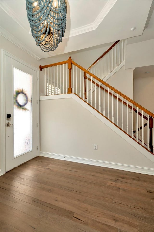 entryway featuring crown molding, baseboards, stairway, wood-type flooring, and an inviting chandelier