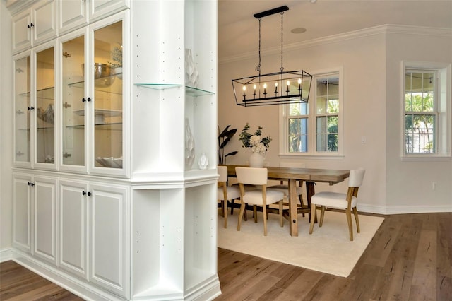 dining space featuring ornamental molding, a chandelier, dark wood finished floors, and baseboards