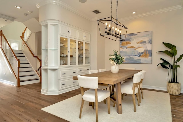 dining room featuring visible vents, stairway, ornamental molding, wood finished floors, and baseboards